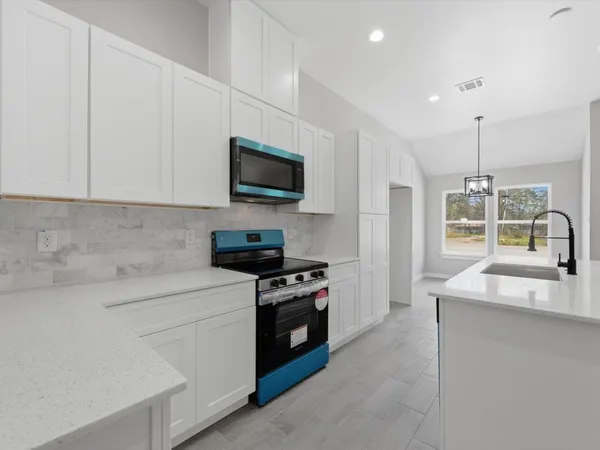 a large kitchen with stainless steel appliances a large counter top and a refrigerator