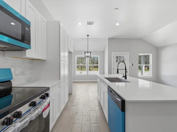 a kitchen with stainless steel appliances a stove top oven a sink a refrigerator and white cabinets