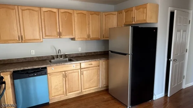 a kitchen with stainless steel appliances granite countertop a refrigerator a sink and dishwasher with wooden cabinets