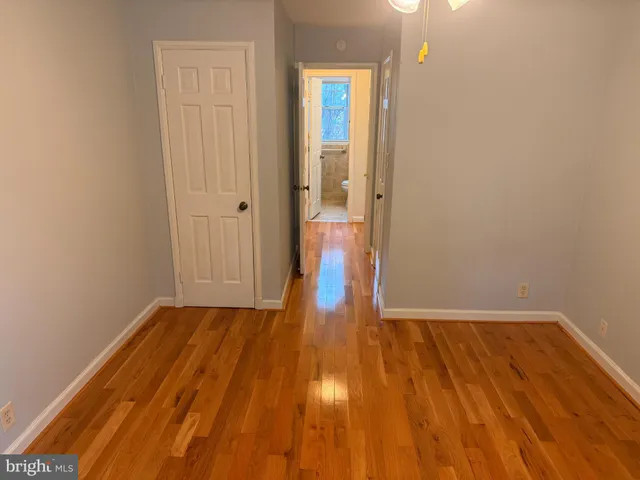 a view of kitchen and empty room with wooden floor