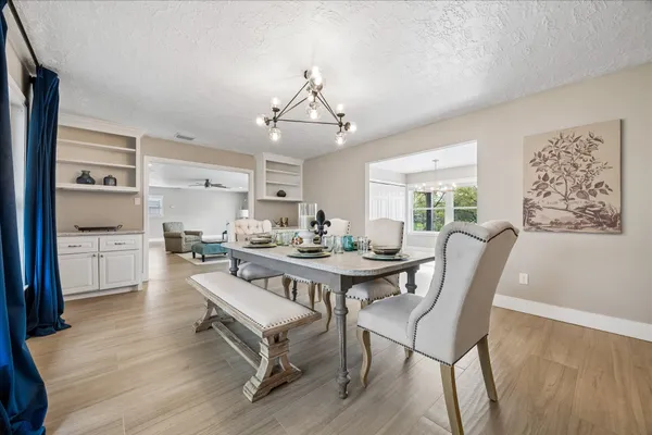 a dining room with furniture a chandelier and wooden floor