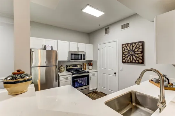 a kitchen with stainless steel appliances a refrigerator sink and white cabinets