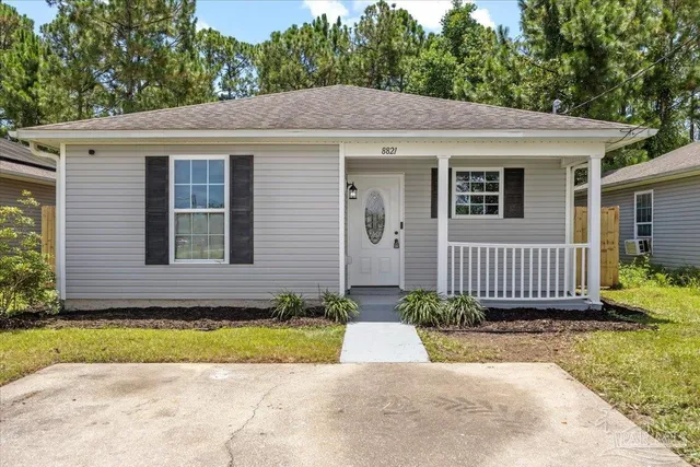 a view of a house with a small yard plants and large tree