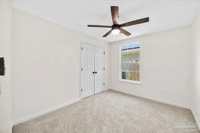 an empty room with ceiling fan and window