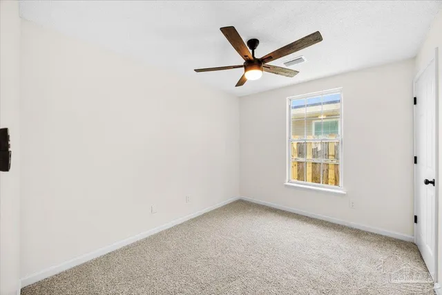 an empty room with a window and a fan