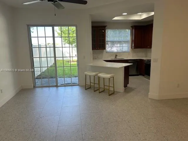 a large white kitchen with granite countertop a large window and a fireplace
