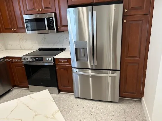 a kitchen with stainless steel appliances granite countertop a refrigerator a stove a microwave and a sink