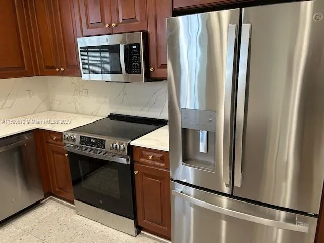 a kitchen with stainless steel appliances granite countertop a refrigerator and a stove
