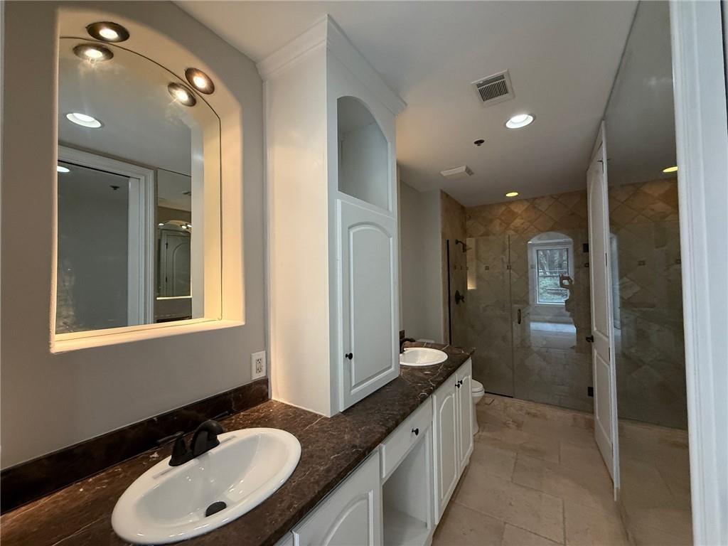 2255 Peachtree Road Northeast, Unit 322 Atlanta, GA 30309 - Photo 12 of 25 a bathroom with a granite countertop sink a mirror and a shower