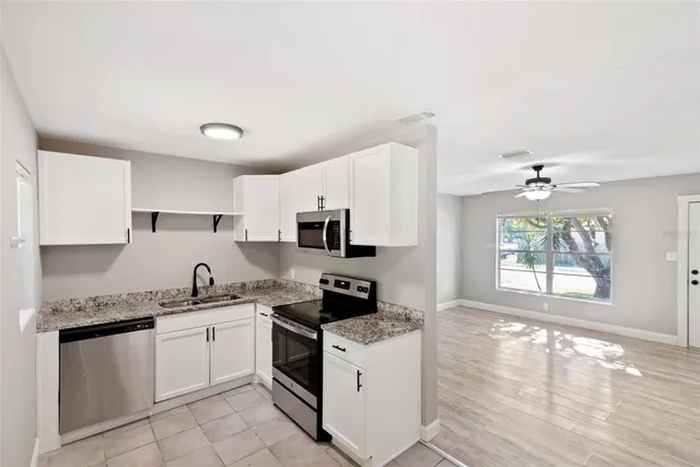 a kitchen with granite countertop a sink stainless steel appliances and cabinets