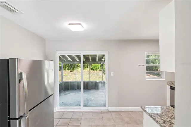 a view of a refrigerator in kitchen and an empty room
