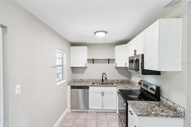 a kitchen with stainless steel appliances granite countertop a sink stove and cabinets