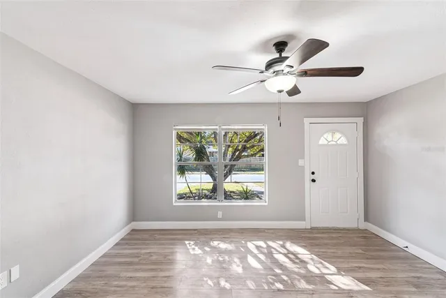 an empty room with windows and ceiling fan