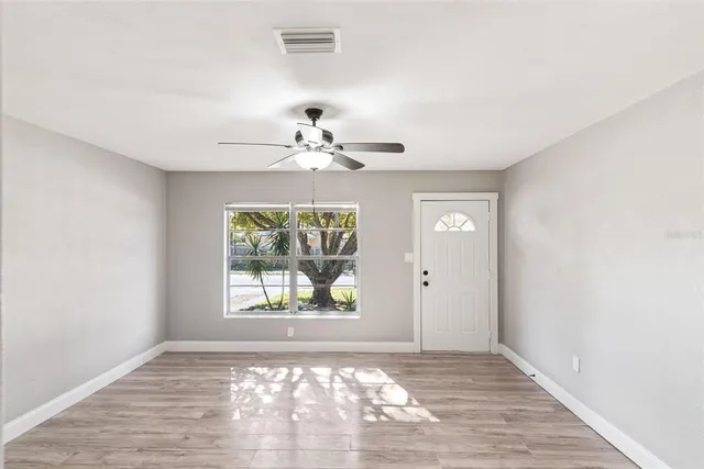 a view of an empty room with window and wooden floor