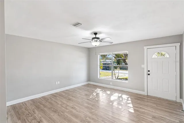 a view of an empty room with window and wooden floor