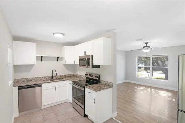 a kitchen with granite countertop a stove top oven sink and cabinets