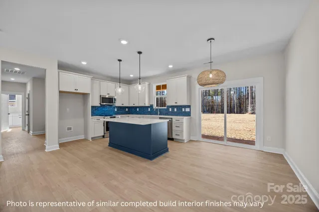 a large kitchen with stainless steel appliances kitchen island a large counter top and a wooden cabinets