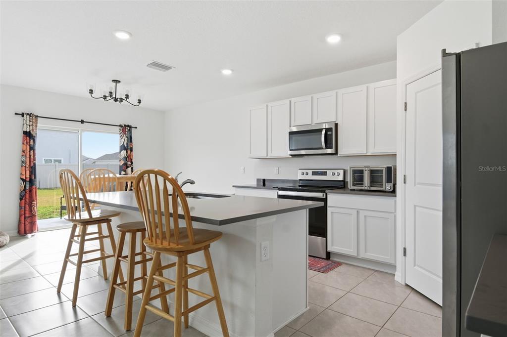 3844 Sunny Spring Street Plant City, FL 33565 - Photo 21 of 26 a kitchen with stainless steel appliances granite countertop a stove a sink a microwave a dining table and chairs
