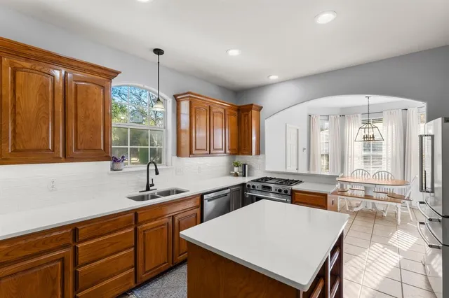 a kitchen with stainless steel appliances a sink stove and white cabinets with wooden floor