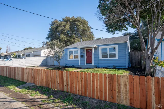 a brick house with wooden fence next to a yard