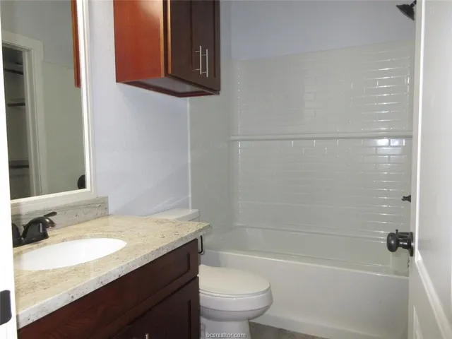a bathroom with a granite countertop sink toilet and shower