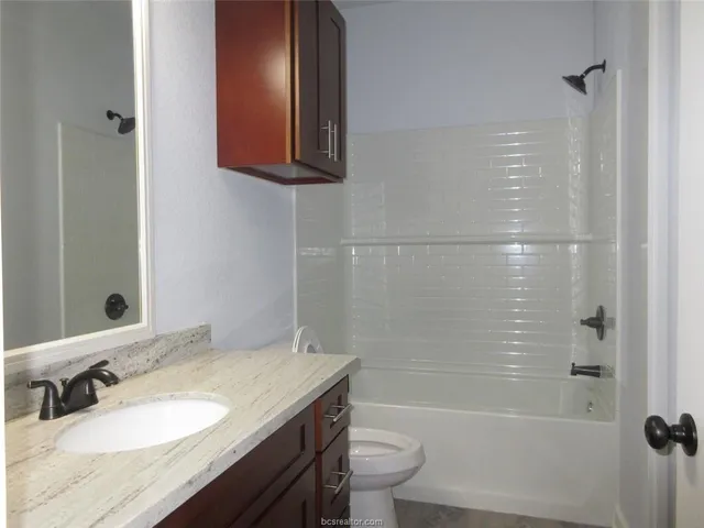 a bathroom with a granite countertop sink toilet and shower