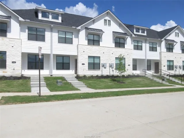 a view of a brick house with a yard in front of it