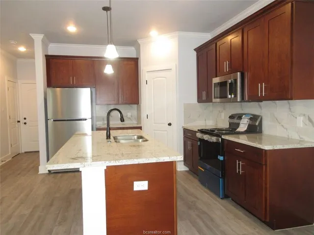 a kitchen with kitchen island granite countertop a sink stainless steel appliances and cabinets