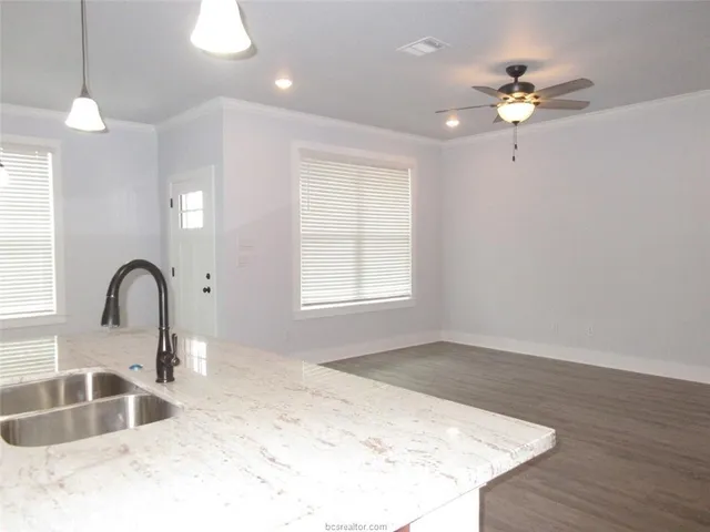 a kitchen with a sink chandelier and living room view