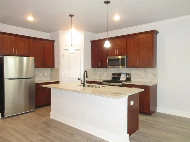 a kitchen with stainless steel appliances granite countertop a sink a stove a refrigerator a center island and cabinets