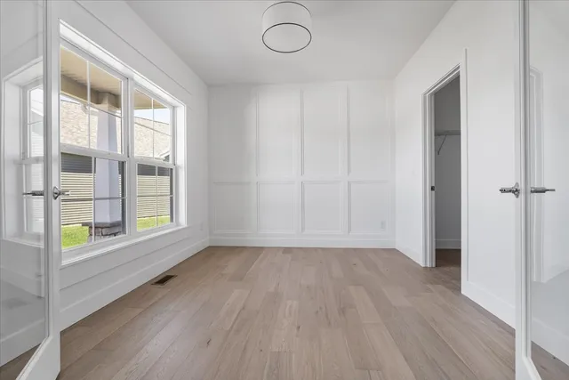 an empty room with wooden floor and windows