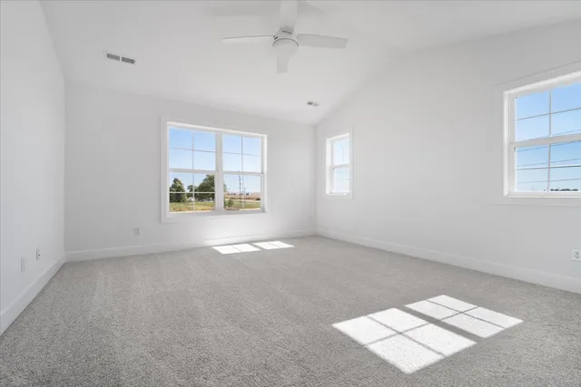 an empty room with windows and chandelier fan