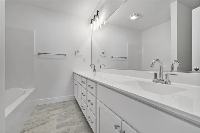 a bathroom with a double vanity sink a mirror and a bathtub