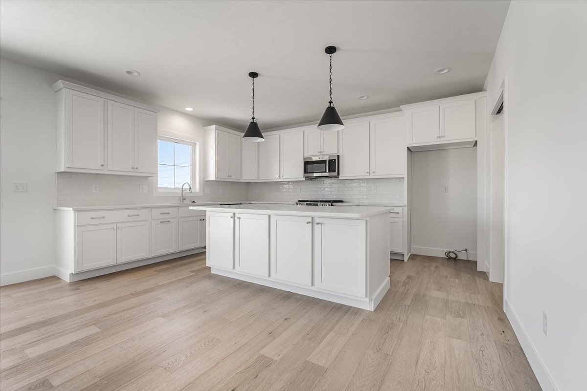 24 Stonehouse Court Bloomington, IL 61705 - Photo 8 of 45 a kitchen with stainless steel appliances white cabinets a sink a window and wooden floors