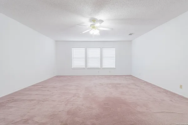 an empty room with a window and a ceiling fan
