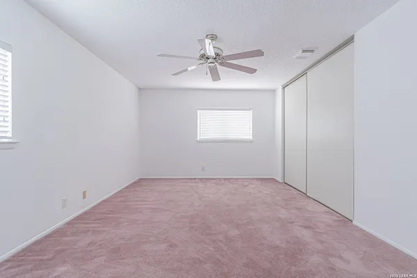 an empty room with windows and fan