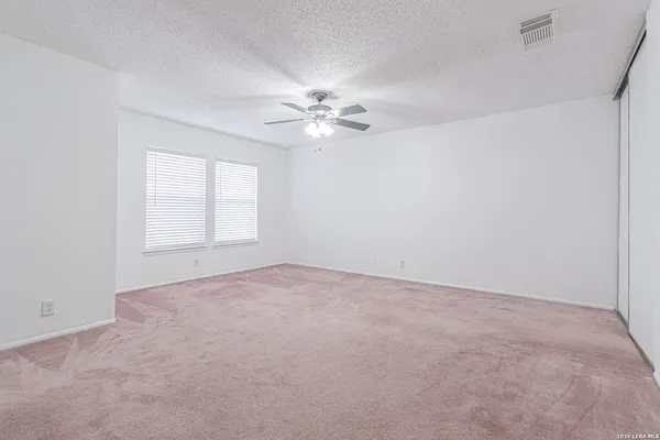 an empty room with a window and a ceiling fan