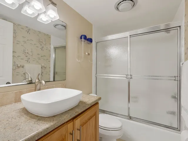 a bathroom with a granite countertop sink toilet and shower