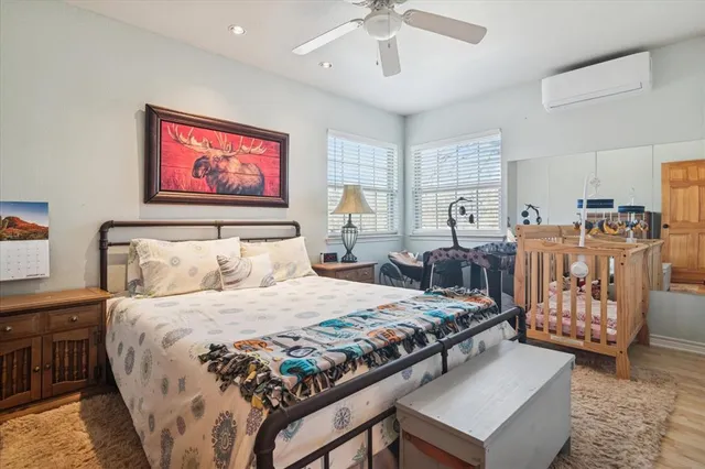 a bedroom with a bed a dresser and potted plant