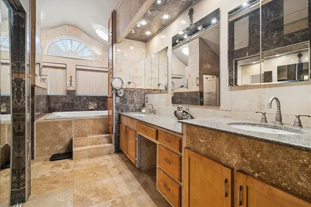 a spacious bathroom with a granite countertop sink a mirror and bathtub