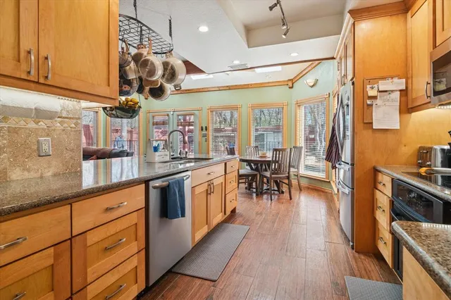 a kitchen with stainless steel appliances granite countertop wooden cabinets a stove top oven a sink and dishwasher