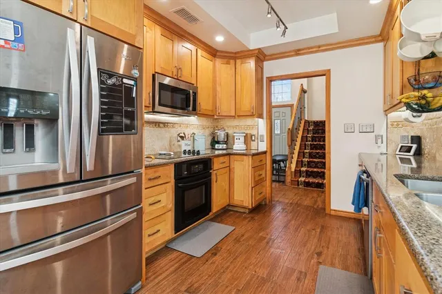 a kitchen with stainless steel appliances granite countertop a stove top oven a sink dishwasher a refrigerator and cabinets with wooden floor