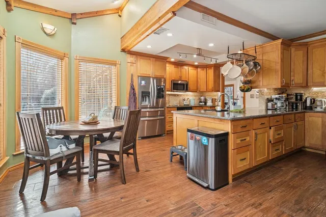 a kitchen with stainless steel appliances granite countertop a table chairs stove and sink