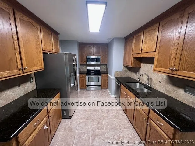 a kitchen with granite countertop a refrigerator stove and sink