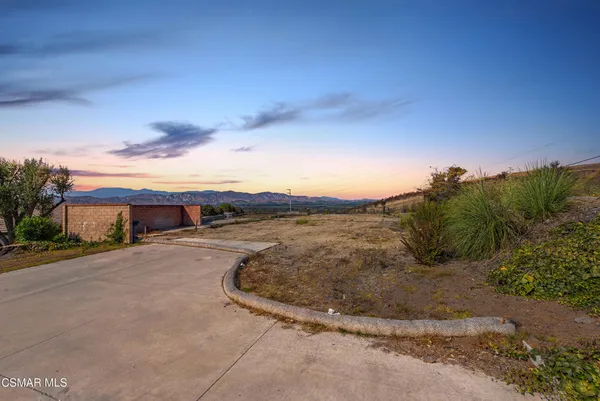 a view of a dry yard with wooden fence