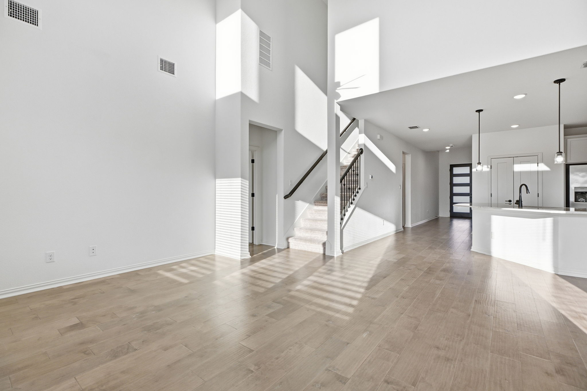 13720 Jon Ryan Road Manor, TX 78653 - Photo 12 of 31 Sun-filled open-concept living space with lofty ceilings and sleek wood flooring, offering a seamless flow into the kitchen.