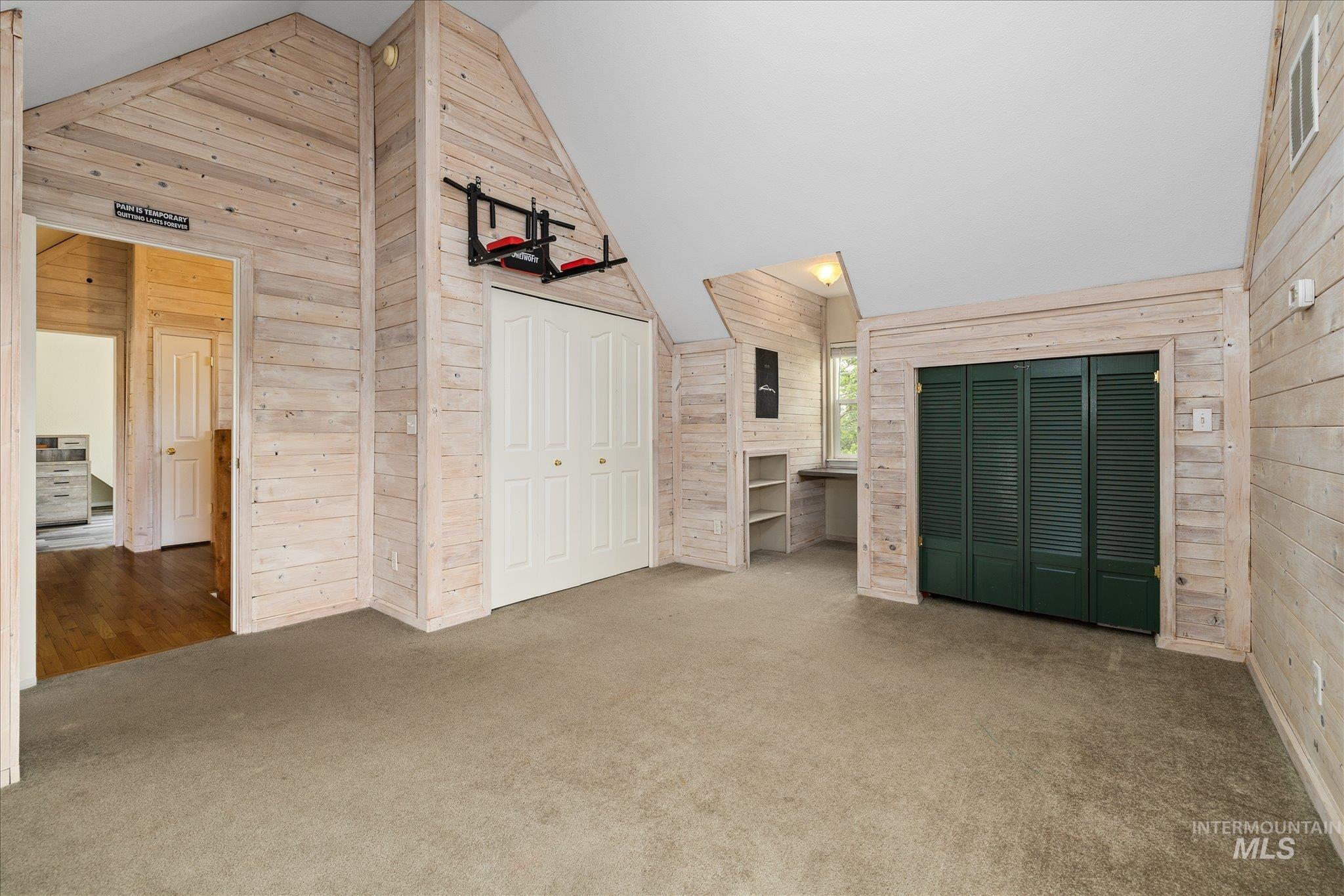 1140 Edgemont Road Emmett, ID 83617 - Photo 23 of 50 Carpeted room featuring shiplap walls, a built-in desk with shelving, and bi-fold closet doors