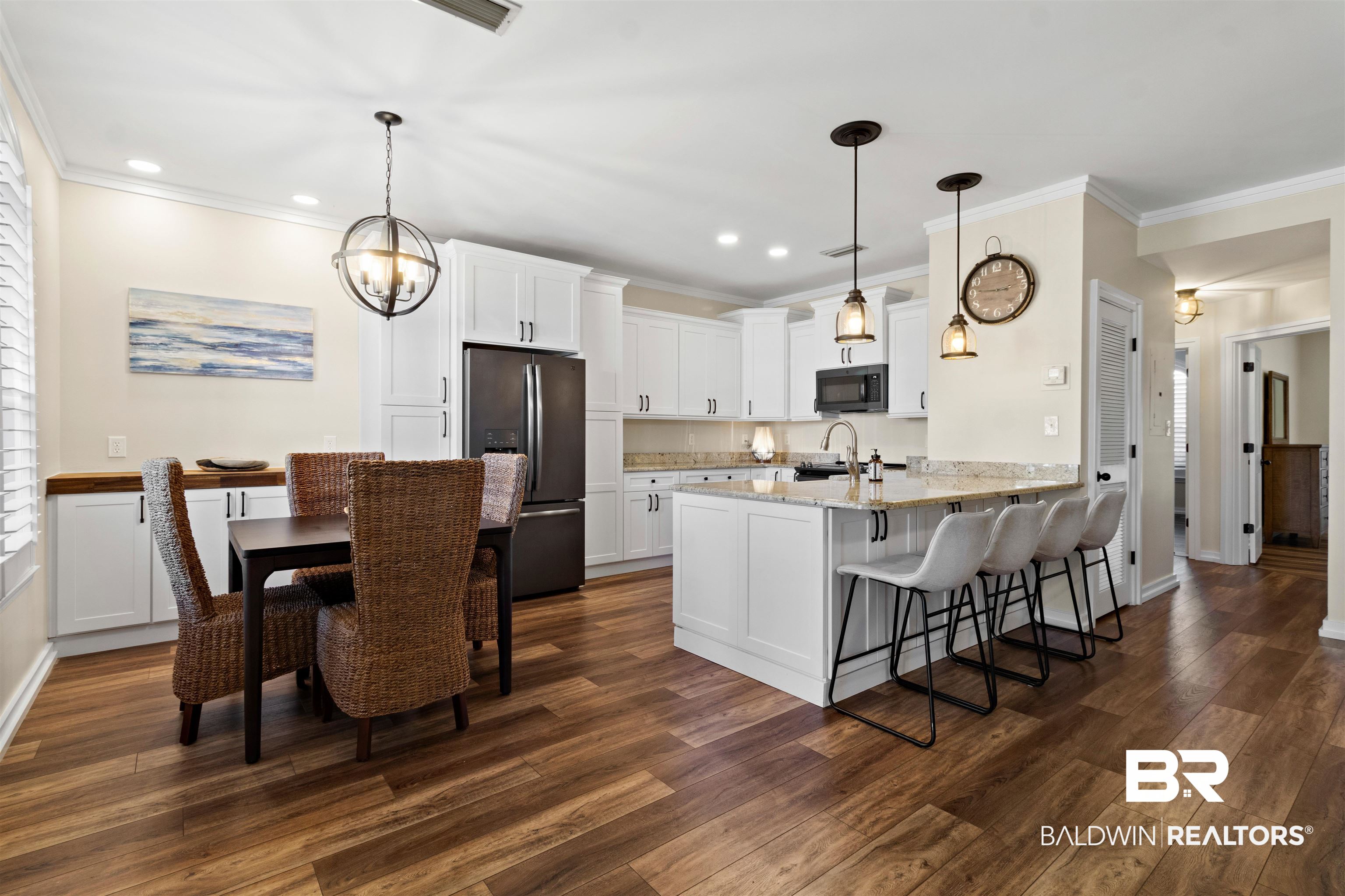 3543 Bayou Road, Unit 5 Orange Beach, AL 36561 - Photo 4 of 33 Open-concept kitchen and dining area featuring wood-finish flooring, white cabinetry, a kitchen island with granite countertop, and integrated stainless steel appliances