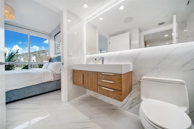 a spacious bathroom with a granite countertop double vanity sink a mirror and a toilet