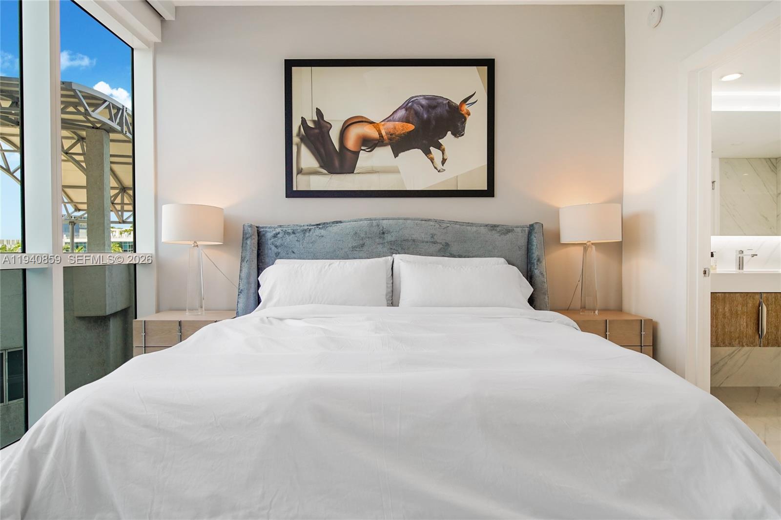 400 Alton Road, Unit 409 Miami Beach, FL 33139 - Photo 16 of 25 a large bed in a bedroom with a painting on the wall and a large window